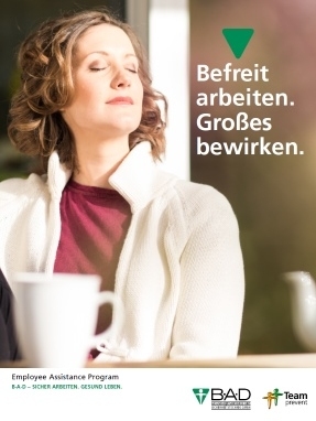 Eine Frau sitzt zufrieden mit ihrer Tasse an einem Tisch und hat die Augen geschlossen.