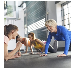 Eine Trainerin motiviert drei Frauen beim Sport.